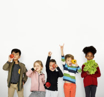 Fünf fröhliche Kinder mit bunter Kleidung halten Gemüse in der Hand