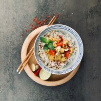 Gemüse-Curry mit Reis, dekoriert mit Stäbchen, Limette und Chili