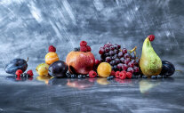 Apfel, Birne, Weintrauben, Zwetschgen und Beeren auf dunkler Fläche